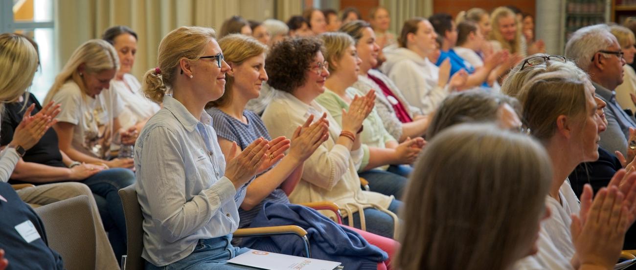 Menschen sitzen in Reihen und klatschen
