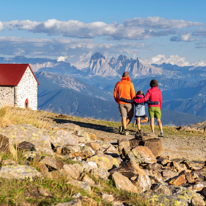 Kleine Familie beim Wandern in den Bergen zu einer Kirche