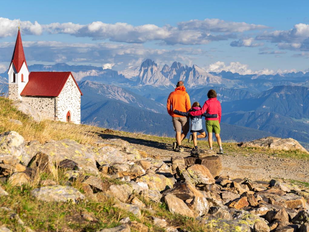 Kleine Familie beim Wandern in den Bergen zu einer Kirche