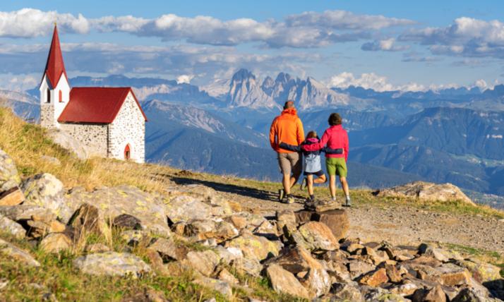 Kleine Familie beim Wandern in den Bergen zu einer Kirche