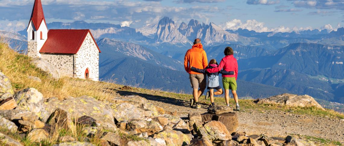 Kleine Familie beim Wandern in den Bergen zu einer Kirche