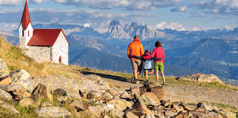 Kleine Familie beim Wandern in den Bergen zu einer Kirche