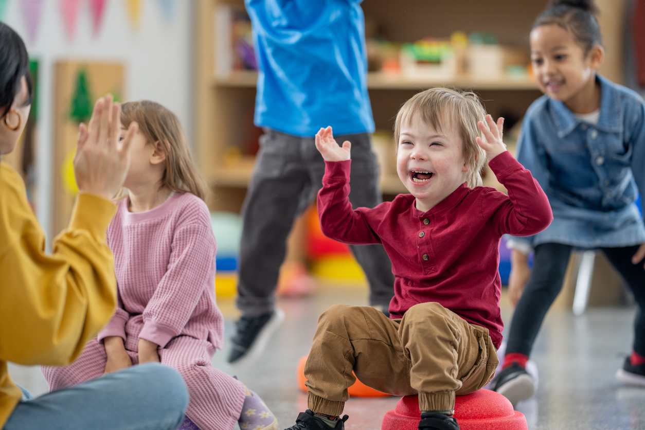 Junge mit Downsyndrom spielt in einer Kindergruppe