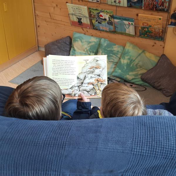 zwei lesende Kinder auf Couch