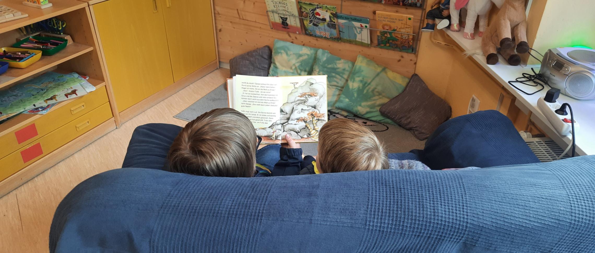 zwei lesende Kinder auf Couch