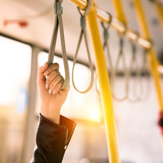 Hand hält sich am Haltegurt einer Straßenbahn fest