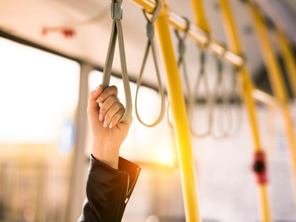 Hand hält sich am Haltegurt einer Straßenbahn fest