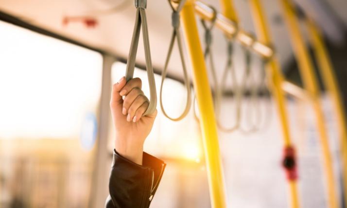 Hand hält sich am Haltegurt einer Straßenbahn fest
