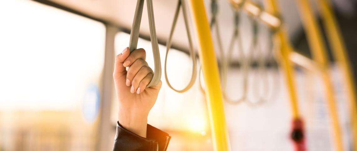 Hand hält sich am Haltegurt einer Straßenbahn fest