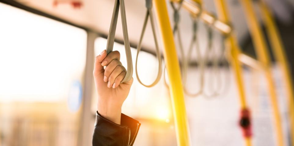 Hand hält sich am Haltegurt einer Straßenbahn fest