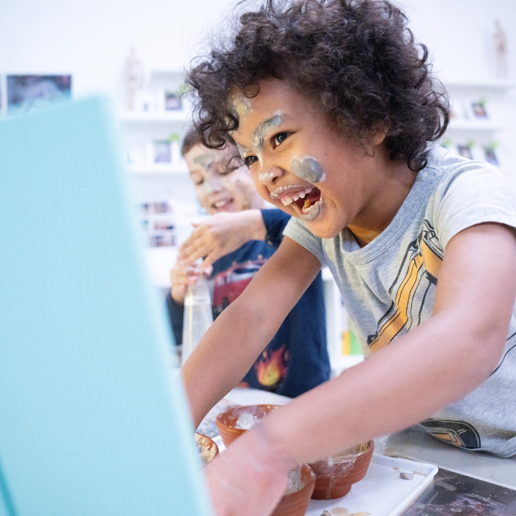 Zwei Kinder lachen und spielen mit bunter Farbe.
