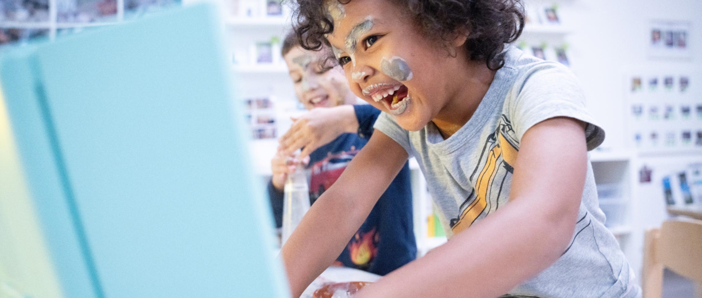 Zwei Kinder lachen und spielen mit bunter Farbe.