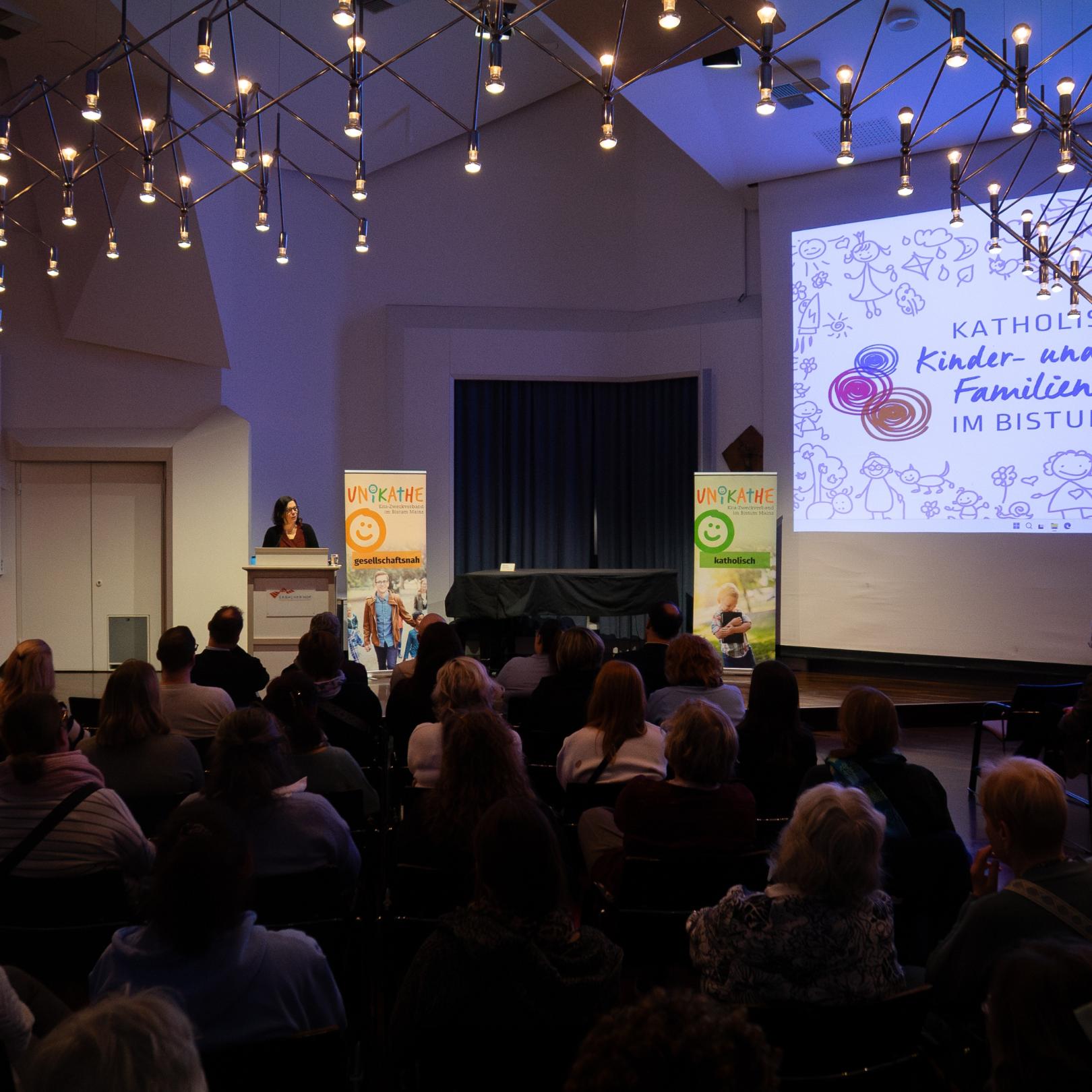 Großer Saal mit vielen sitzenden Menschen die einer Frau am Rednerpult zuhören